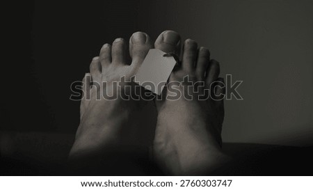 The foot of a labeled corpse in dramatic dark color.