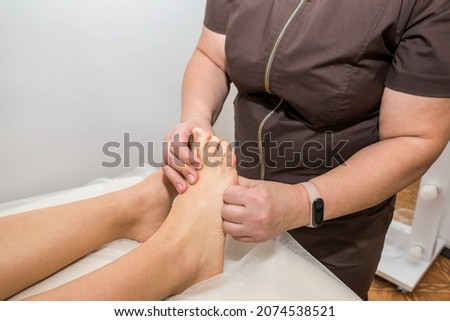 foot massage close up. Woman masseuse massages female legs in massage parlor