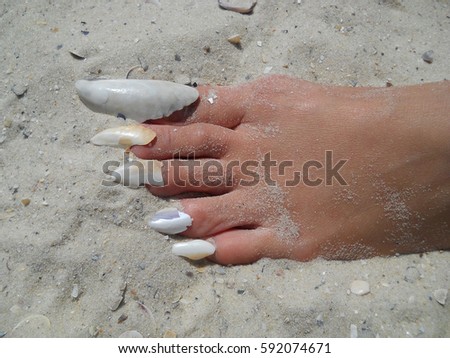 Foot on sand with shell nails