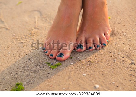 Foot on sea sand. Women's and children's feet in the sand. Beautiful pedicure. Photo for fashion, travel, social magazines and websites. A beautiful photo for background. 