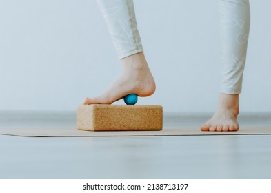 Foot on small therapy ball on cork block for plantar fascia massage and hydration. Concept: self care practices at home, myofascial release