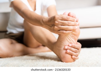 Foot pain, Asian woman feeling pain in her foot at home, female suffering from feet ache use hand massage relax muscle from soles in home interior, Healthcare problems and podiatry medical concept - Shutterstock ID 2136320133