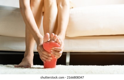 Foot Pain, Asian Woman Sitting On Sofa Feeling Pain In Her Foot At Home, Female Suffering From Feet Ache Use Hand Massage Relax Muscle From Soles In Home Interior, Healthcare And Podiatry Medical