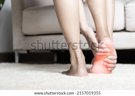 Foot pain, Asian woman standing feeling pain in her foot at home, female suffering from feet ache use hand massage relax muscle from soles in home interior, Healthcare problems and podiatry medical Zdjęcia stock © 