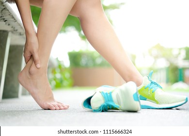 Foot Pain Leg of woman which runner athletic by running shoes sitting on grass in the park holding he feet and stretch the muscles in morning sunlight .Health care and spa concept - Powered by Shutterstock