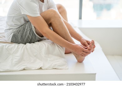 Foot pain, man suffering from feet ache at home, podiatry concept - Shutterstock ID 2103432977
