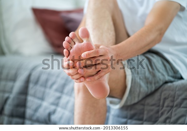 Foot pain, man suffering from feet ache in home\
interior, podiatry concept