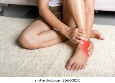 Foot Pain, Woman Holds Her Ankle Injury Feeling Pain In Her Foot At Home, Female Suffering From Feet Ache Use Hand Massage Relax Muscle From Ankle In Home Interior, Healthcare Problems And Medical