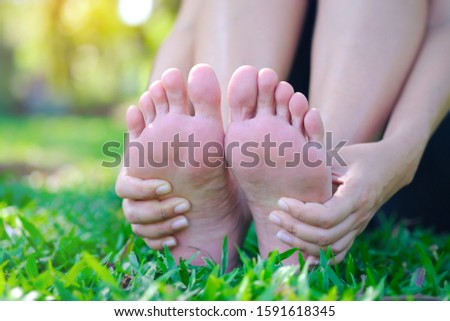 Foot pain .Woman sitting on grass Her hand caught at the foot. Having painful feet and stretching muscles fatigue To relieve pain. health concepts