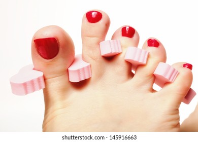 foot pedicure applying woman's feet with red toenails in toe separators white background