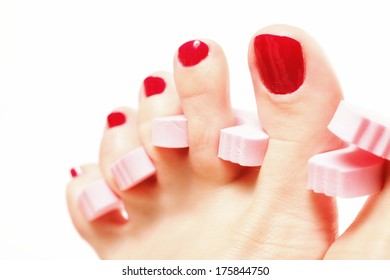 foot pedicure applying woman's feet with red toenails in toe separators white background