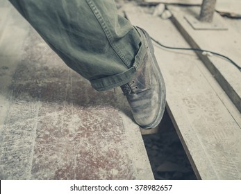 The Foot Of A Person Tripping On A Gap Between The Floor Boards In A Room Undergoing Renovations