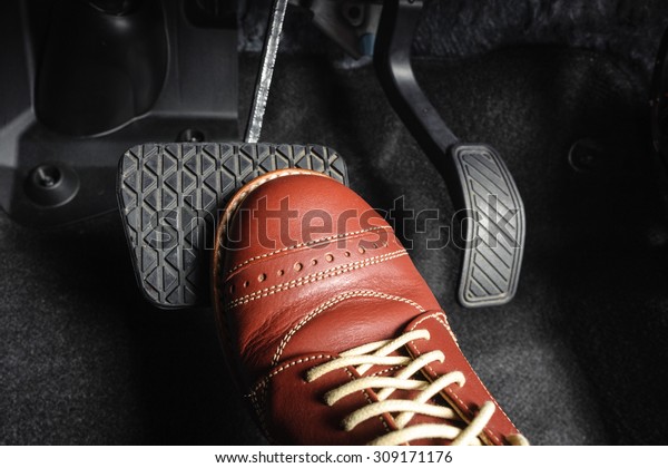 foot pressing the brake\
pedal of a car