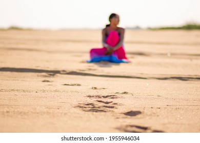 Foot Print On A Beach Leading To A Blurred Lady Sitting Down