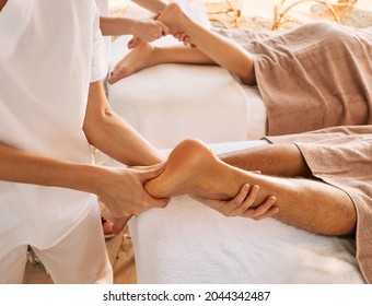 Foot reflexology, foot massage close-up. Masseurs press on special foot points for feet massage of a man and a woman in a spa salon - Powered by Shutterstock