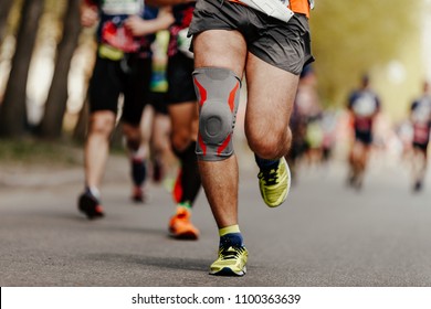 Foot Runner Man In Knee Pads Running Ahead Of Group Marathon Runners