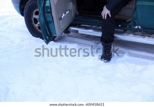 A foot\
stepping out of a car on the snowy\
ground