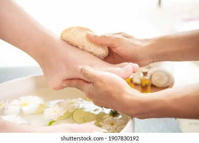 Foot Washing In Spa Before Treatment. Spa Treatment And Product For Female Feet And Hand Spa. White Flowers In Ceramic Bowl With Water For Aroma Therapy At Spa.