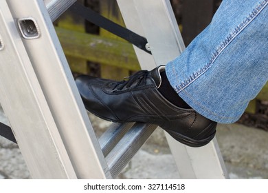 Foot Of Woman In Black Shoes On Aluminum Ladder In Garden