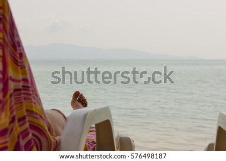 Foot of woman lying on beach hammock by the sea on cloudy day in the island of Koh Phangan overlooking at Koh Samui on the background, Thailand. Summer vacation, chill out, relax concepts