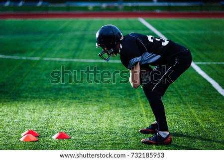 A footbal player down on one knee praying