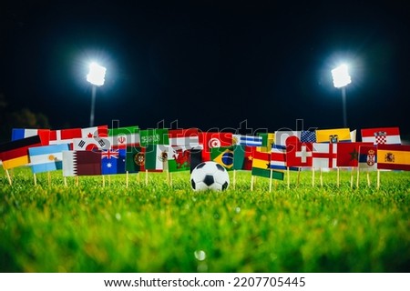 Football ball and 32 national flags on green grass. Concept photo for world football tournament.