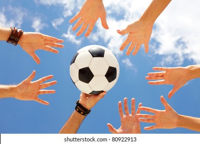 A football ball in circle of hands - Powered by Shutterstock