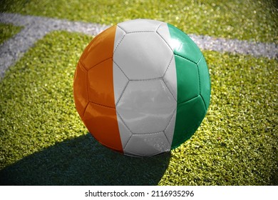 football ball with the national flag of cote divoire lies on the green field near the white line