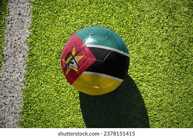 football ball with the national flag of mozambique on the green field near the white line