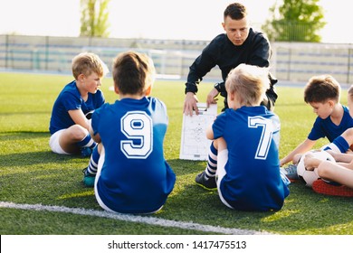 Football Coach Coaching Kids. Soccer Football Training Session For Young Boys. Young Coach Teaching Children On Football Field. Football Tactic Education. Coach Explains The Strategy Of The Game