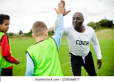 Football coach doing a high five with his student - Powered by Shutterstock