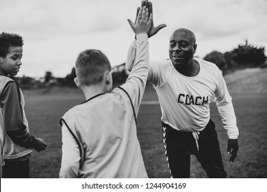 Football coach doing a high five with his student - Powered by Shutterstock