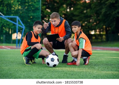 Football Coach Instruct Teen Football Players. Young Professional Coach Explains For Kids The Strategy Of The Game.