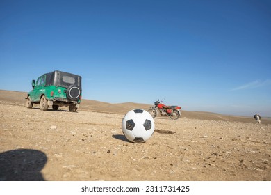 football in a desert near car and bike - Shutterstock ID 2311731425
