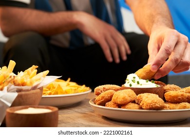 football fan eating snacks served on a wooden table