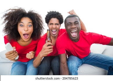 Football Fans In Red Cheering On The Sofa With Beers On White Background