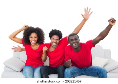 Football fans in red cheering on the sofa on white background - Powered by Shutterstock