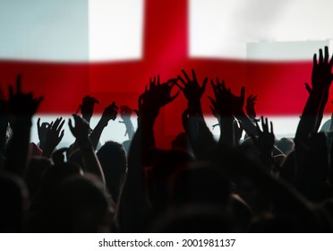 Football fans supporting England - crowd celebrating in stadium with raised hands against England flag