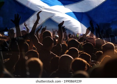 football fans supporting Scotland - crowd celebrating in stadium with raised hands against Scotland flag