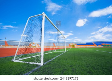 Football field with goal and tablo on blue sky