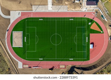 Football field, soccer stadium and red running track top aerial view. Photo from a quadcopter. View from above.