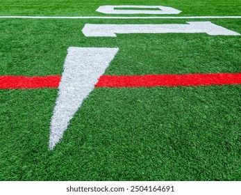 Football Field Turf Ten Yard Line. American football field with bright green artificial turf. Ten yard line markings with arrow. Horizontal yard marking lines in red and white. - Powered by Shutterstock