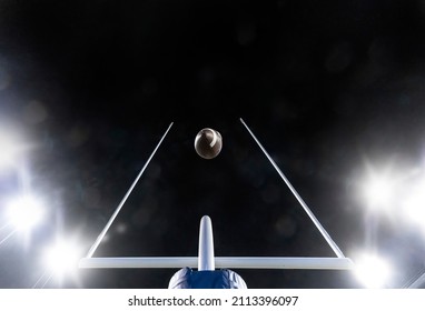 Football flying through the uprights of the field goal posts during a night football game	