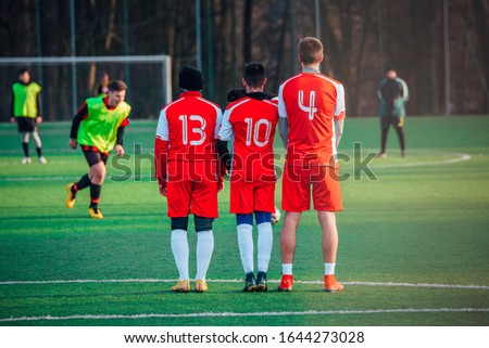Football free kick, soccer concept photo, players in red jerseys, green grass sunset light