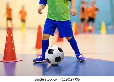 Football futsal training for children. Soccer training dribbling cone drill. Indoor soccer young player with a soccer ball in a sports hall. Player in blue uniform. Sport background. - Powered by Shutterstock