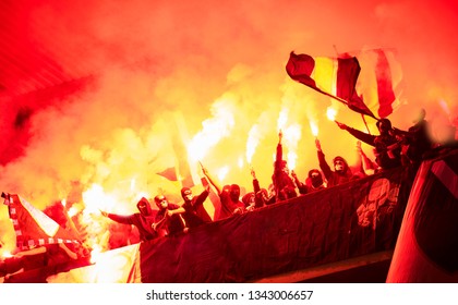 football hooligans with mask holding torches in fire while supporting their favorite team during a match at stadium - Shutterstock ID 1343006657