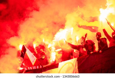 football hooligans with mask holding torches in fire while supporting their favorite team during a match at stadium - Shutterstock ID 1343006663