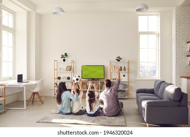 Football match, leisure and happy family sport fan pastime together. Excited parent with overjoyed children watching soccer game on tv sitting on floor carpet in living room at home. Rear view