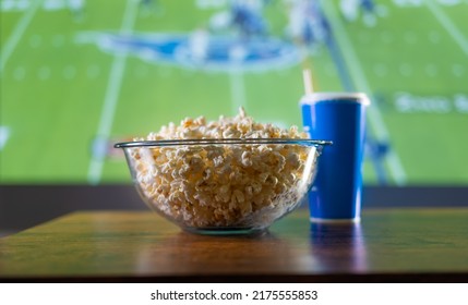 Football Match On Big Screen TV. On The Table Is A Bowl Of Popcorn And A Drink In A Glass. Watch Your Favorite Sports Programs On TV, Football, American Football. Cold Appetizers, Home Comfort.