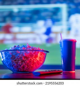 Football Match On The Big Screen Plasma TV. On The Table Is A Bowl Of Popcorn, A Soda Drink In A Plastic Cup, And A Remote Control. Watching Sports Programs On TV, Fast Food.